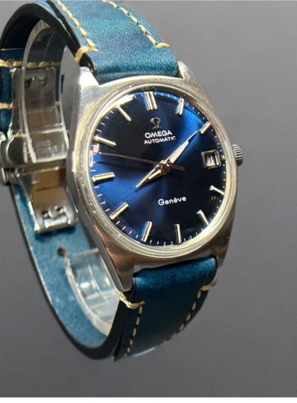 Seiko watch with a blue dial and leather strap resting on a textured wooden surface, alongside a second leather strap in a luxurious case.